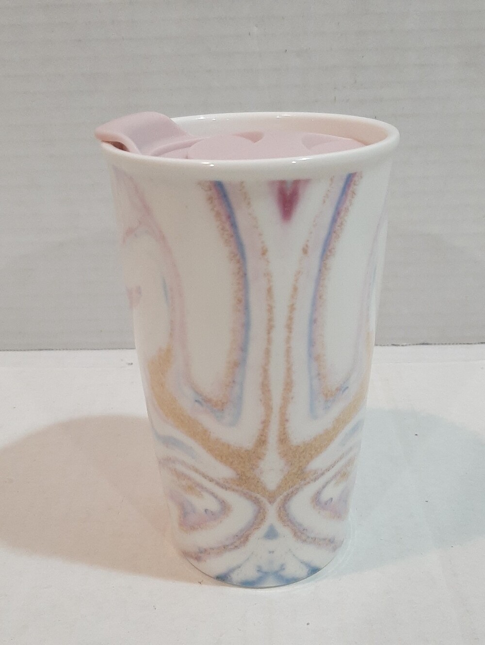 Ceramic travel mug featuring a pastel marbled pattern and a light pink lid